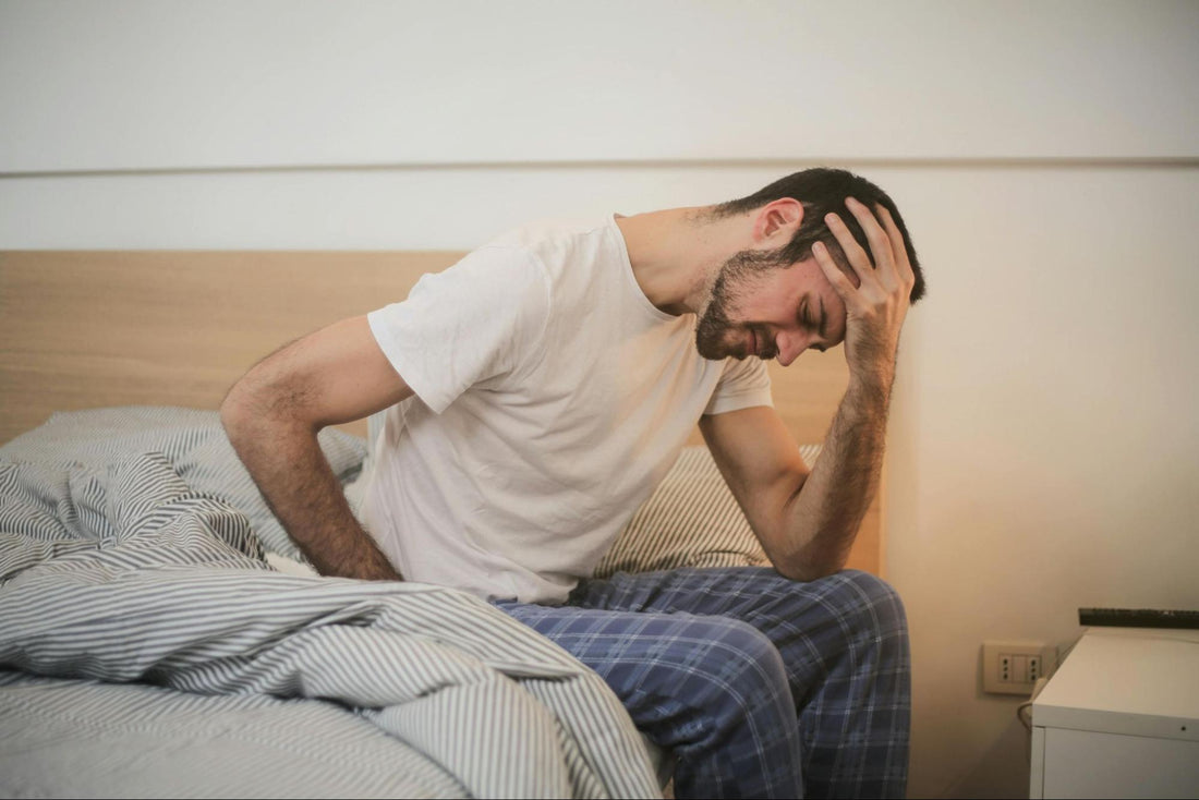 Man Holding Head in Bed