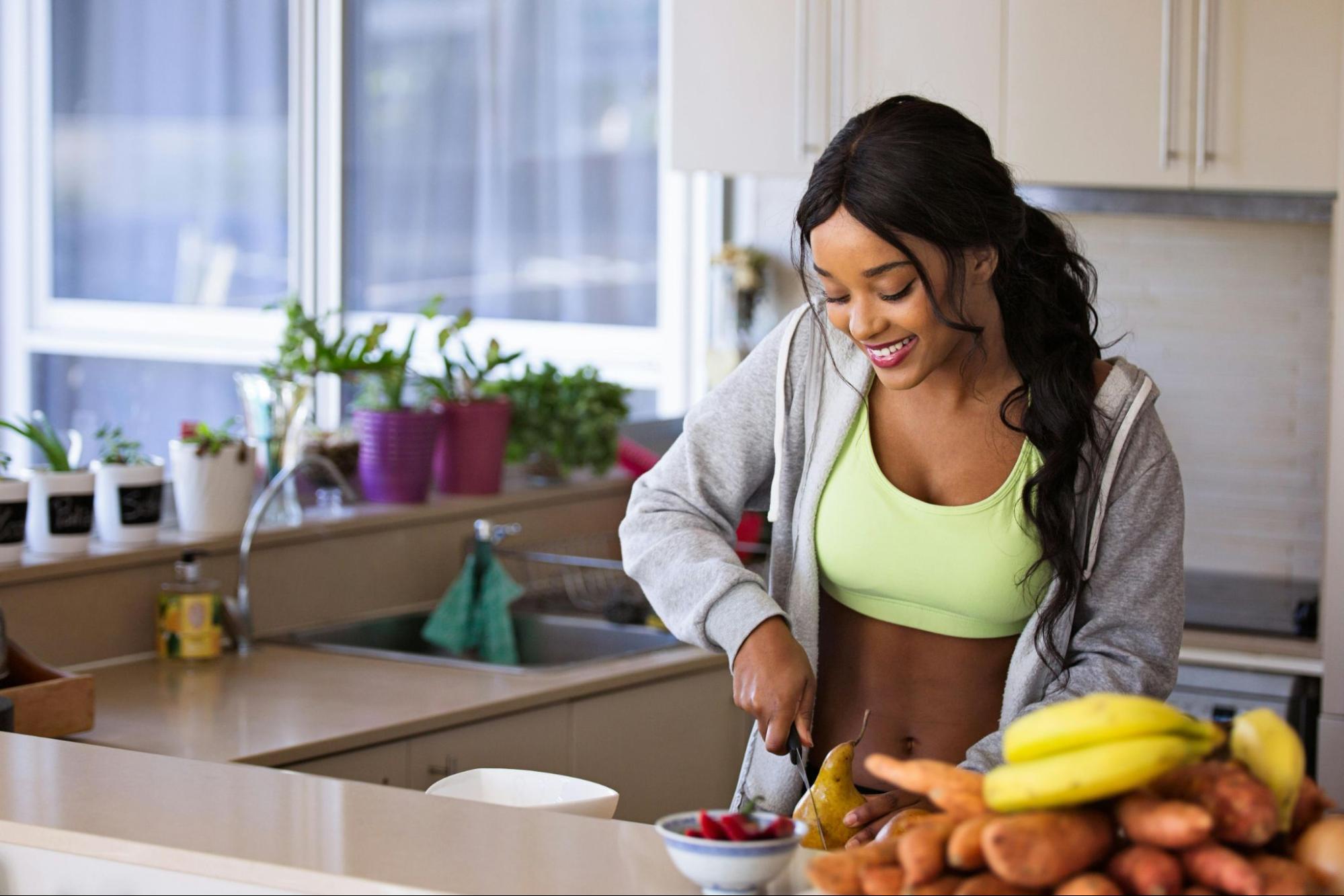 Woman Cutting Fruit in Workout Outfit