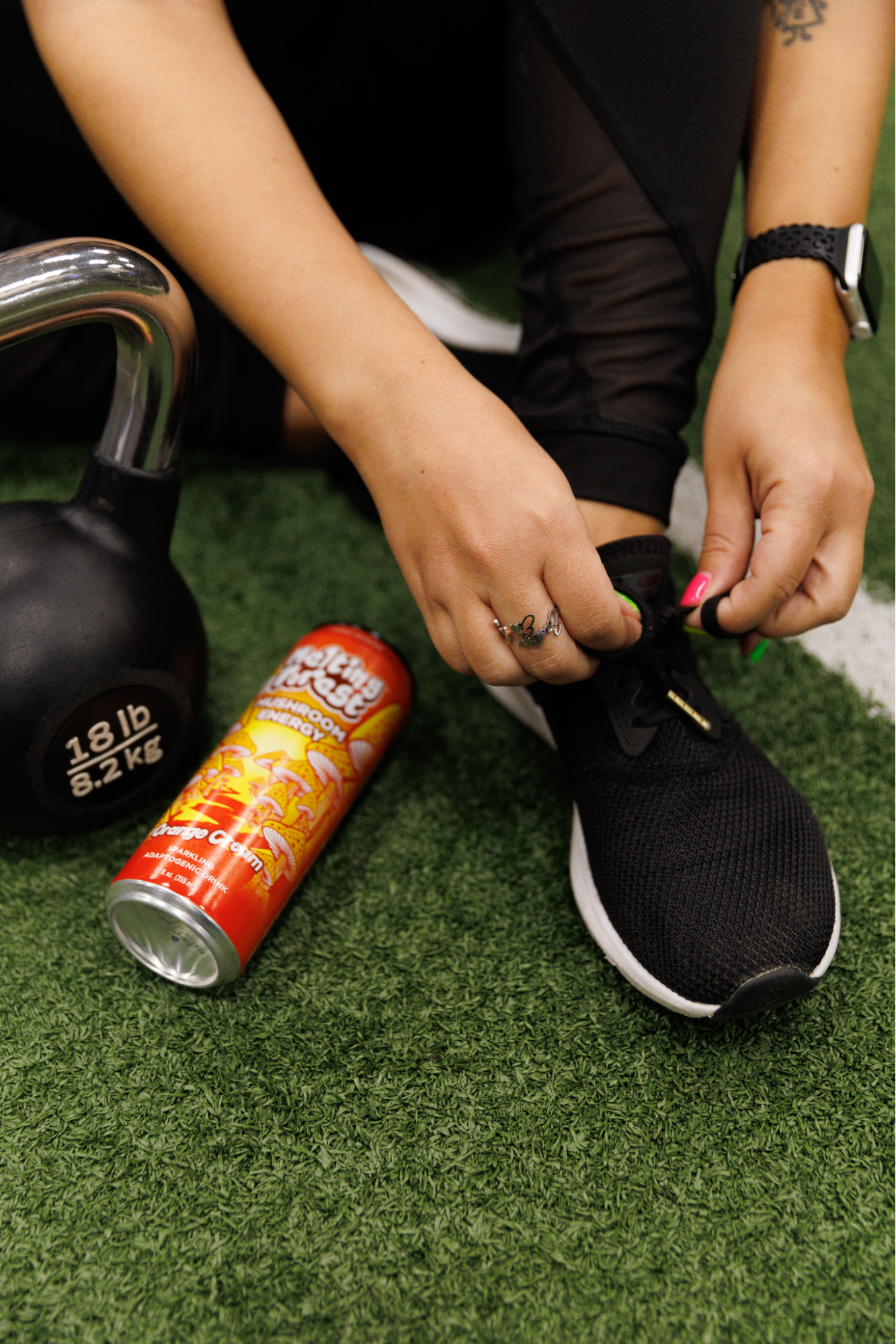 A person tying their shoelaces with a mushroom drink next to them.